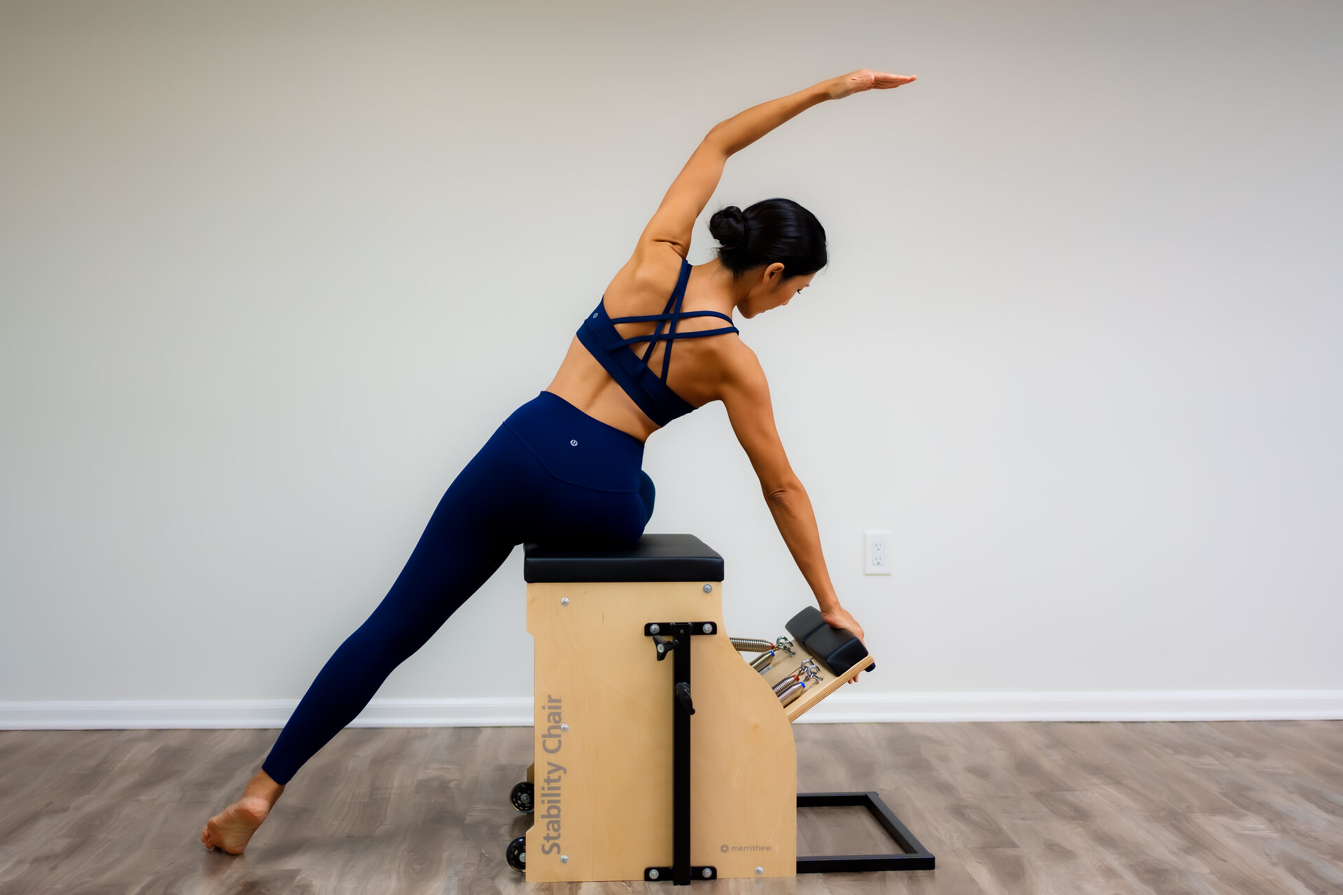 A balanced side-plank reach supported on the ladder barrel.